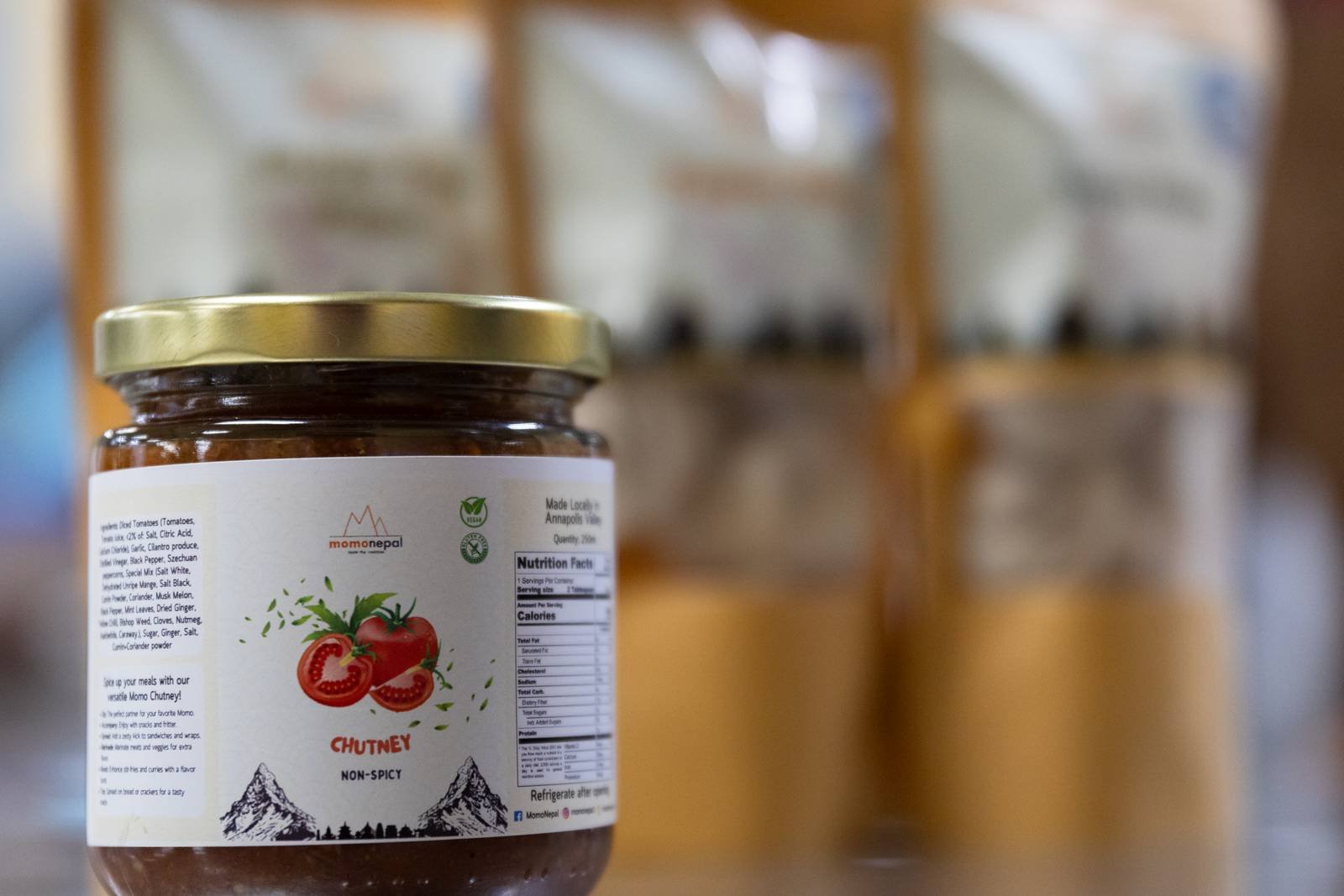 A jar of MomoNepal tomato chutney in front of frozen momo packs